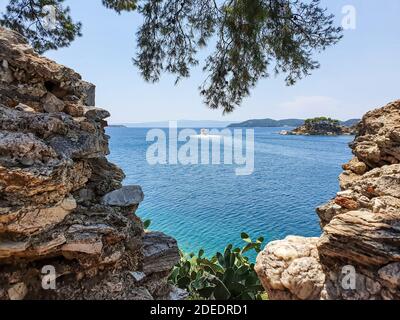 Blick durch Steine auf die Altstadt von Skiathos auf der Insel Skiathos, Griechenland. Stockfoto