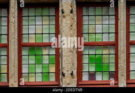 Grüntöne: Typische flämische, mit Steinpflöckchen verbleitete Lichtfenster mit kleinen, grün, gelb und lila getönten Glasscheiben in einem alten Haus in der Nähe der Wasserburg der Grafen in Gent, Ostflandern, Belgien. Stockfoto