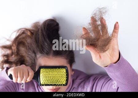 Mädchen hält in der Hand Sperre von verlorenen Haaren und Augen schließen mit Haarbürste, auf einem weißen Hintergrund. Stockfoto