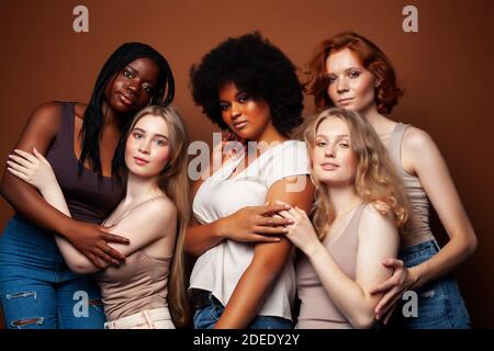 Junge hübsche kaukasische, afro, skandinavische Frau posiert fröhlich zusammen auf braunem Hintergrund, Lifestyle diverse Nationalität Menschen Konzept Stockfoto
