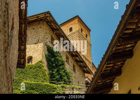 Außenansicht des Schlosses von Serralunga mit Turm und Ziegelhäusern - Stadt Serralunga, Italien, Piemont Stockfoto