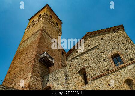 Außenansicht des Schlosses von Serralunga mit Turm und Ziegelhäusern - Stadt Serralunga, Italien, Piemont Stockfoto