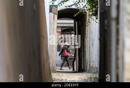 Passau, Deutschland. November 2020. Eine Frau mit Mundschutz geht an einer Gasse vorbei. Nach Angaben des Robert Koch-Instituts (RKI) ist die niederbayerische Stadt Passau zusammen mit dem Thüringer Stadtteil Hildburghausen der Top-Corona-Hotspot in Deutschland. Quelle: Armin Weigel/dpa/Alamy Live News Stockfoto