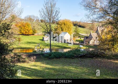 Herbst in den Cotswolds - der kleine See am Bach hinter Manor Farm in Middle Duntisbourne, Gloucestershire UK