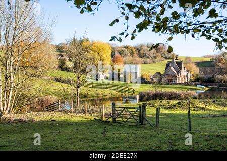 Herbst in den Cotswolds - der kleine See am Bach hinter Manor Farm in Middle Duntisbourne, Gloucestershire UK