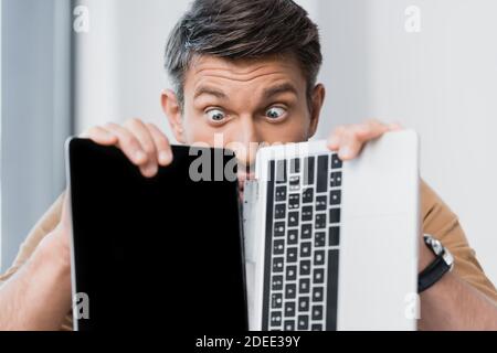 Überrascht Geschäftsmann Blick auf defekten Laptop auf verschwommenem Hintergrund Stockfoto