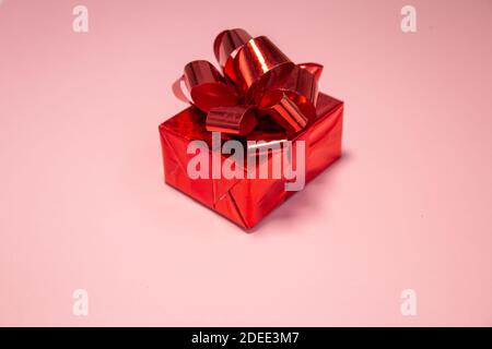 Rote Geschenkbox mit rosa Hintergrund. Minimaler Valentinstag Konzept. Stockfoto