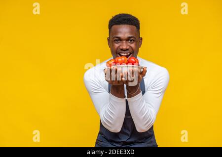 Porträt eines begeisterten und glücklichen afrikanischen Koch hält ein Teller mit Tomaten Stockfoto