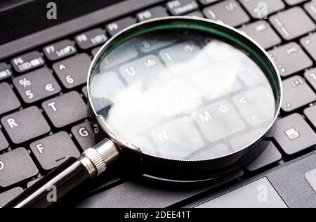 Vergrößerungsglas auf einer Laptop-Tastatur. Loupe auf einem Netbook Schlüssel.Technologie-Datei-Suche-Tool Konzept, Daten Forensik, Computerkriminalität Stockfoto