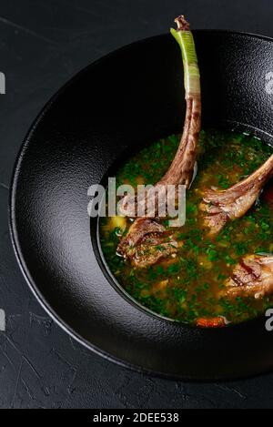Fleischsuppe mit einem Lammrücken auf einem schwarzen Hintergrund Stockfoto