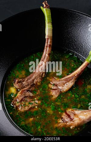 Fleischsuppe mit einem Lammrücken auf einem schwarzen Hintergrund Stockfoto