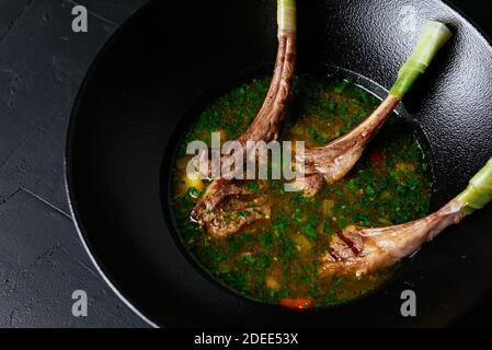 Fleischsuppe mit einem Lammrücken auf einem schwarzen Hintergrund Stockfoto