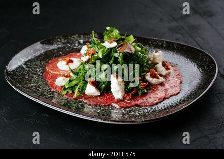 Carpaccio aus Rindfleisch aus Marmor auf schwarzem Hintergrund Stockfoto