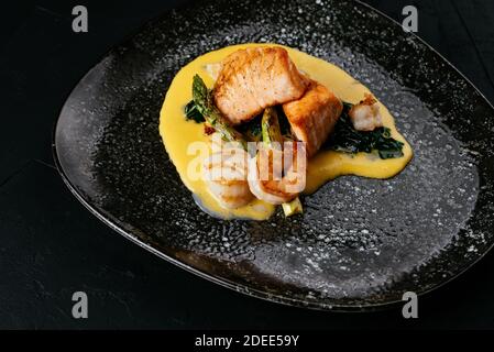 Gegrillter Lachs und Garnelen auf schwarzem Hintergrund Stockfoto
