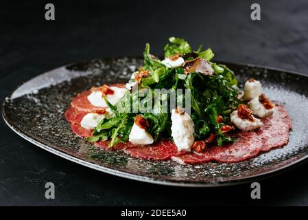 Carpaccio aus Rindfleisch aus Marmor auf schwarzem Hintergrund Stockfoto