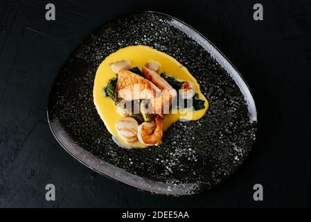 Gegrillter Lachs und Garnelen auf schwarzem Hintergrund Stockfoto