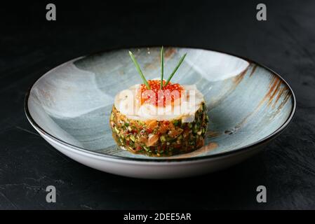 Frische Lachstartare mit rotem Kaviar auf schwarzem Hintergrund Stockfoto