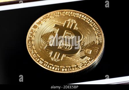 Bitcoin-Symbol, einzelne glänzende Goldmünze auf Smartphone-Bildschirm, Detailaufnahme, Makro, extreme Nahaufnahme, Draufsicht. Bitcoin Kryptowährung Logo, btc Stockfoto