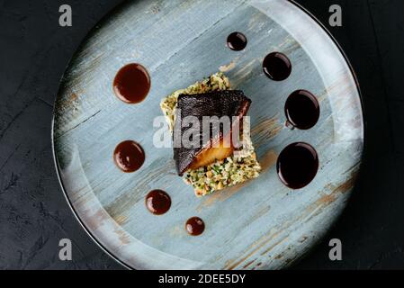 Gegrillter Fisch mit Reis und Gemüse auf schwarzem Hintergrund Stockfoto