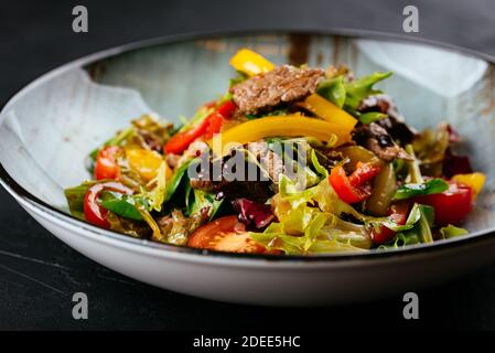 Warmer Salat mit marmorierten Rindersteaks auf schwarzem Hintergrund Stockfoto