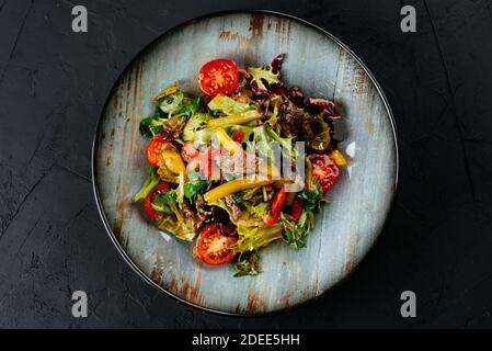 Warmer Salat mit marmorierten Rindersteaks auf schwarzem Hintergrund Stockfoto