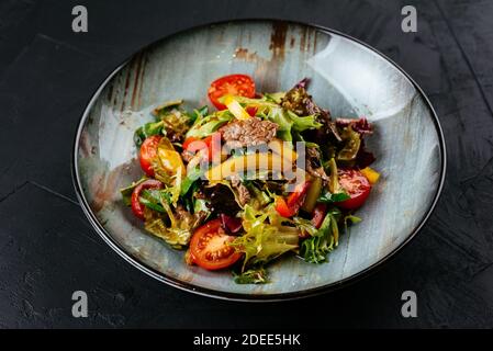 Warmer Salat mit marmorierten Rindersteaks auf schwarzem Hintergrund Stockfoto