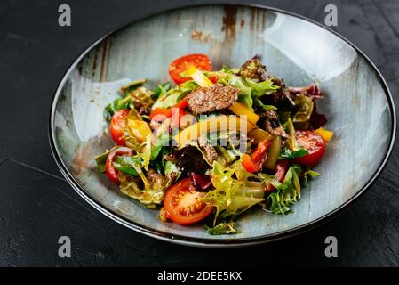 Warmer Salat mit marmorierten Rindersteaks auf schwarzem Hintergrund Stockfoto