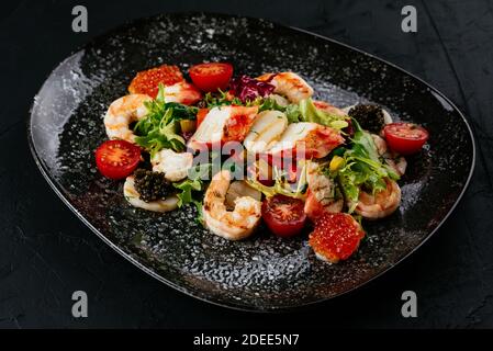 Salat mit Garnelen, Gemüse und Krabbenfleisch auf schwarzem Hintergrund Stockfoto