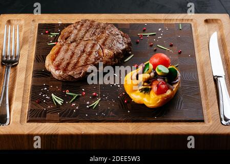 Marmoriertes Rindersteak mit Gemüse und Sauce auf einem schwarzen Hintergrund Stockfoto