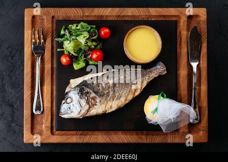 Gegrillter Dorado mit Gemüse auf schwarzem Hintergrund Stockfoto