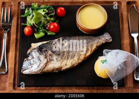 Gegrillter Dorado mit Gemüse auf schwarzem Hintergrund Stockfoto
