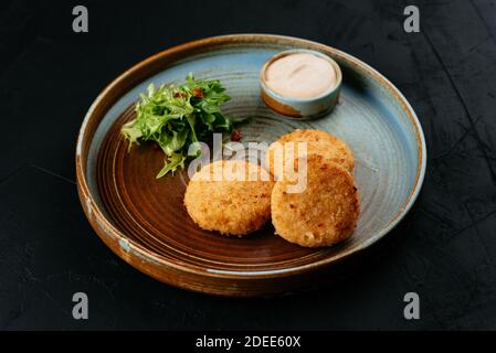 Gegrillte Lachsschnitzel mit Sauce auf schwarzem Hintergrund Stockfoto