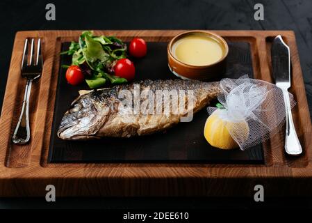 Gegrillter Dorado mit Gemüse auf schwarzem Hintergrund Stockfoto