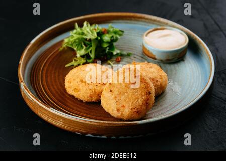 Gegrillte Lachsschnitzel mit Sauce auf schwarzem Hintergrund Stockfoto