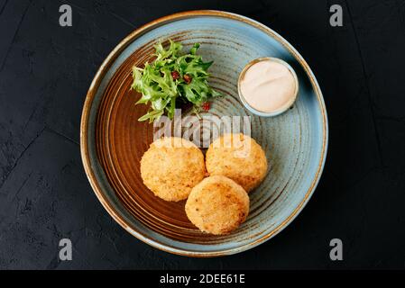 Gegrillte Lachsschnitzel mit Sauce auf schwarzem Hintergrund Stockfoto