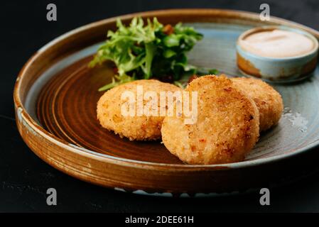 Gegrillte Lachsschnitzel mit Sauce auf schwarzem Hintergrund Stockfoto