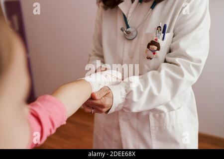 Ärztin verband den Arm eines kleinen Mädchens in ihrem Zimmer. Hausarzt Konzept Stockfoto