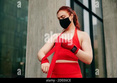 Junge Boxerin, Umhüllung Handgelenk in Brooklyn Street, mit Gesichtsmaske. Stockfoto