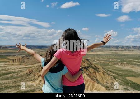 Kleine Schwestern im Blickpunkt beobachten mit offenen Armen einen Wüstenberg im Nationalpark Bardenas Reales in Navarra, Spanien. Reisekonzept Stockfoto