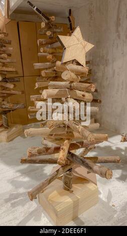 Dekorativer Weihnachtsbaum aus Holz. Stilvolles weihnachtliches Interieur im rustikalen Stil. Handgefertigte festliche Dekorationen. Foto vom iPhone Stockfoto