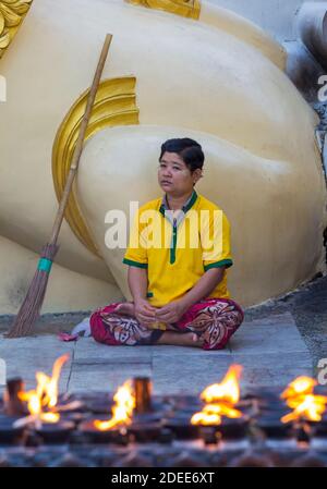 Mann, der sich im Februar in der Shwedagon Pagode, Yangon, Myanmar (Burma), Asien neben dem Besen mit Kerzenflammen hinsetzt Stockfoto