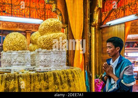 Mann betet vor vier kleinen Buddhas, die mit Gold bedeckt sind, Phaung Daw Oo Paya Pagode, Inle Lake, Myanmar Stockfoto