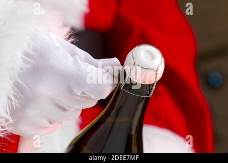 Mann im weihnachtsmann Kostüm öffnet eine Flasche Champagner Stockfoto