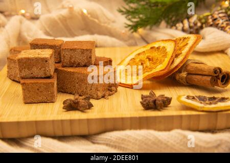 Duftende Gewürze und Marshmallows auf einem Holztablett, verziert mit Tannenzweigen und einer festlichen Girlande. Stockfoto