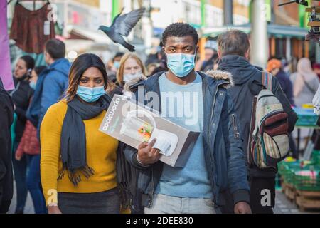 London, Großbritannien - 3. November 2020 - EIN schwarzes Paar mit Gesichtsmasken beim Einkaufen auf dem Walthamstow Markt Stockfoto