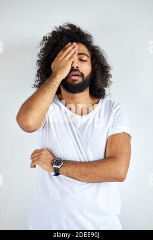 Trauriger arabischer Mann hat Probleme, er ist deprimiert, hält Hand am Kopf, steht in Gedanken, isoliert auf weißem Hintergrund Stockfoto