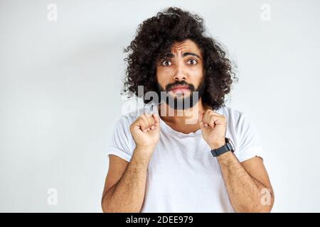 Erschrocken lockig arabischen jungen Kerl stehen in Angst vor etwas, Blick auf Kamera, isoliert auf weißem Hintergrund. Stockfoto