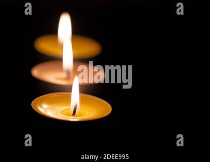 Drei Teelichter vor schwarzem Hintergrund Stockfoto