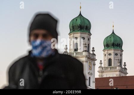 Passau, Deutschland. November 2020. Ein Mann geht mit einer Gesichtsmaske vor den Stephansdom. Nach Angaben des Robert Koch-Instituts (RKI) ist die niederbayerische Stadt Passau zusammen mit dem Thüringer Stadtteil Hildburghausen der Top-Corona-Hotspot in Deutschland. Quelle: Armin Weigel/dpa/Alamy Live News Stockfoto