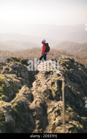 Voll ausgestatteter Bergsteiger mit Rucksack steht auf dem felsigen Aussichtspunkt Stockfoto